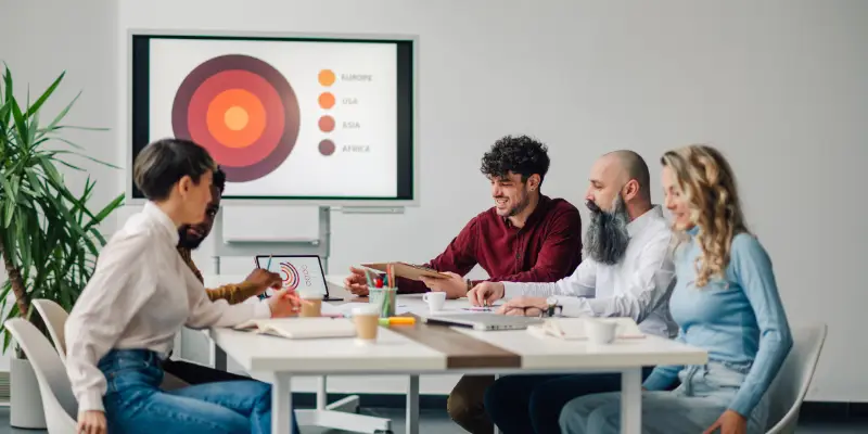 Ausarbeitung einer Werbestrategie: Teammeeting im Büro mit Präsentation auf dem Bildschirm – Zusammenarbeit und Strategieentwicklung